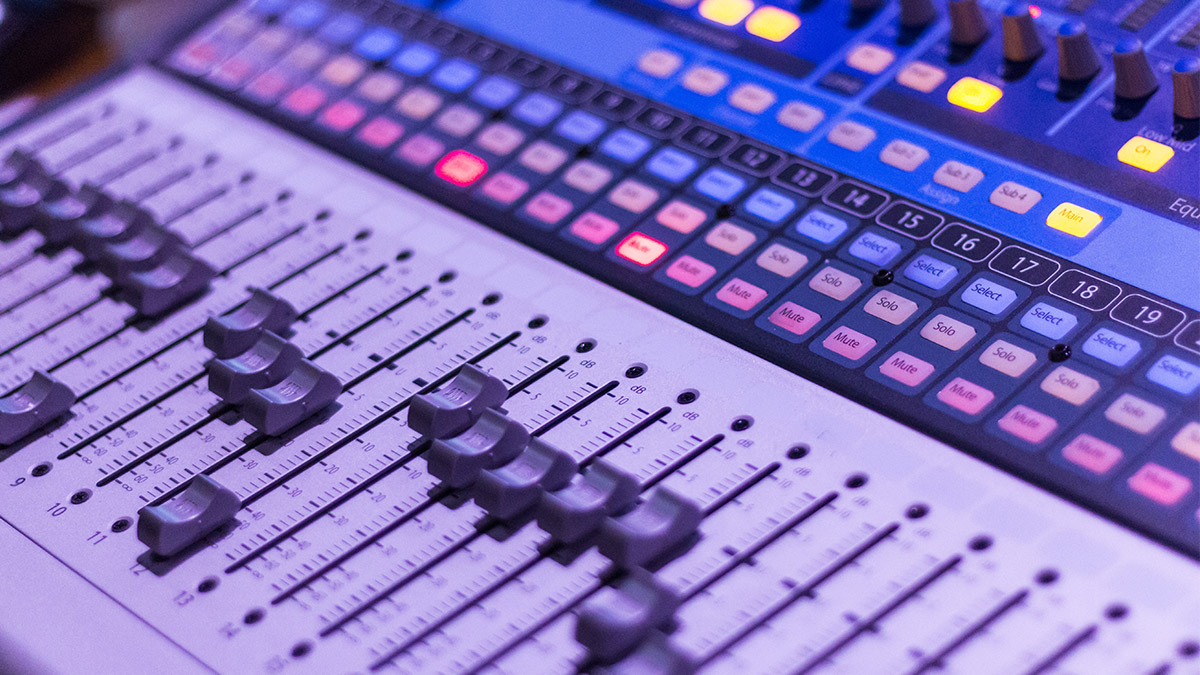 Close-up of a music mixing panel with buttons, dials, and sliders