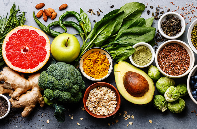 Birds-eye view of an assortment of colourful fruit and vegetables on a grey table.