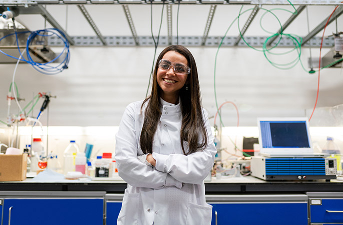 Woman standing next to chemistry bench in a laboratory.
